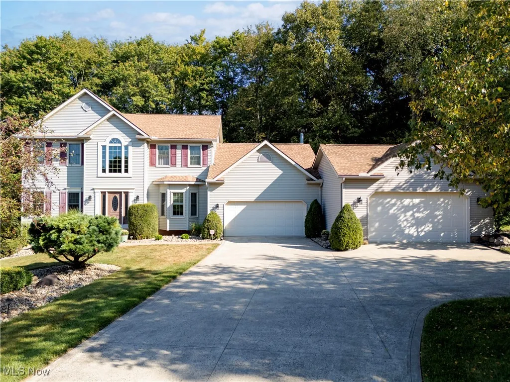 Colonial house with concrete driveway, roof with shingles, and an attached garage