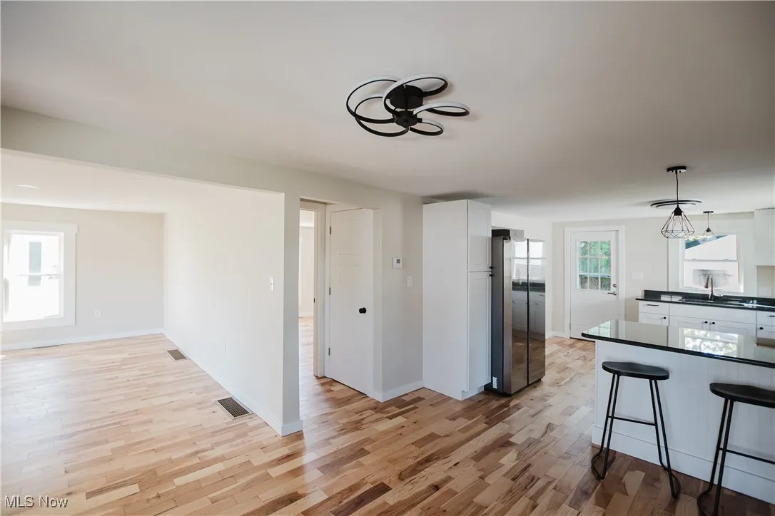 Dining Area featuring white cabinets, dark countertops, decorative light fixtures, freestanding refrigerator, and light wood-type flooring
