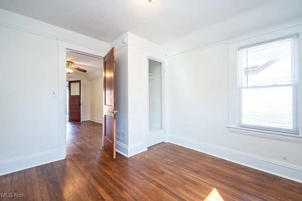 Unfurnished bedroom featuring dark wood-style floors and baseboards