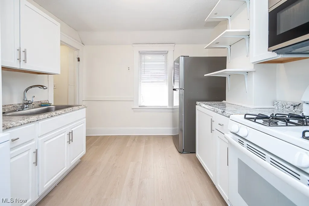 Kitchen featuring gas range gas stove, stainless steel microwave, and white cabinetry