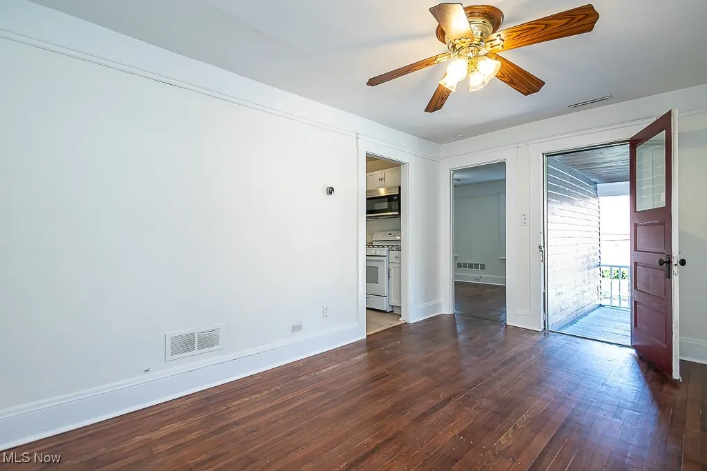 Unfurnished bedroom featuring dark wood finished floors, access to exterior, and ceiling fan