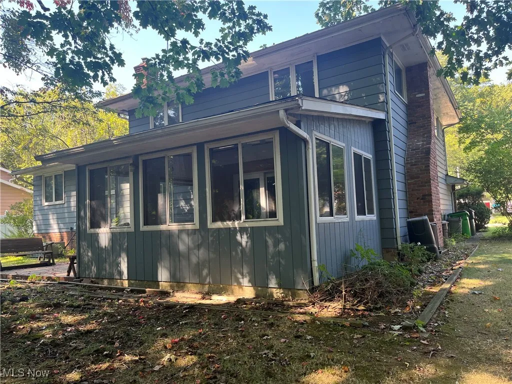 View of home's exterior with a sunroom and a chimney