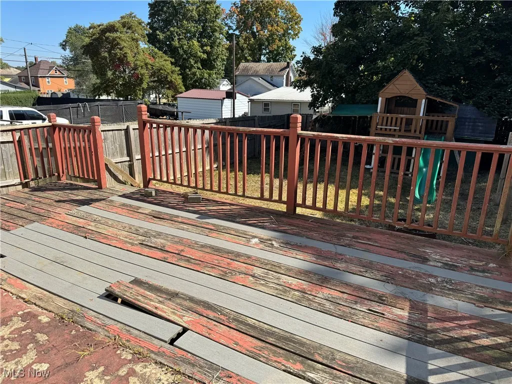 Deck featuring a playground and a fenced backyard