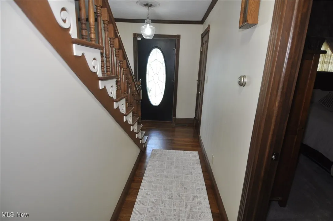 Doorway featuring crown molding, stairs, and wood finished floors