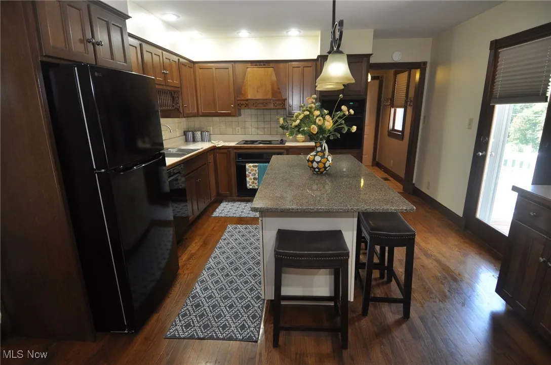 Eat in kitchen featuring breakfast bar, fully applianced, door to rear small deck overlooking pool area and back yard