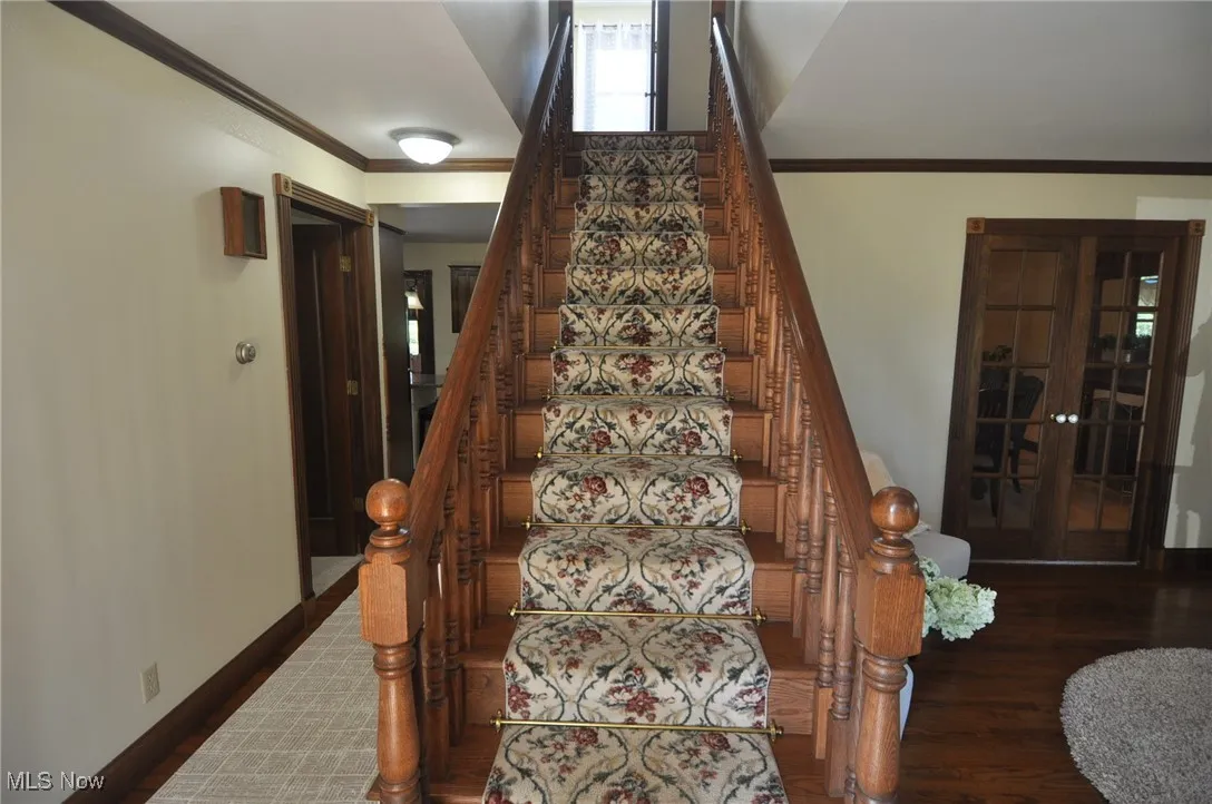 Staircase featuring ornamental molding and wood finished floors