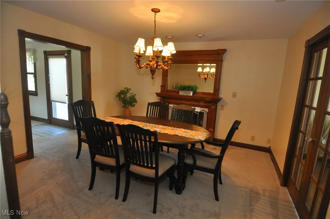 Dining room featuring gas log fireplace, light carpet and a chandelier
