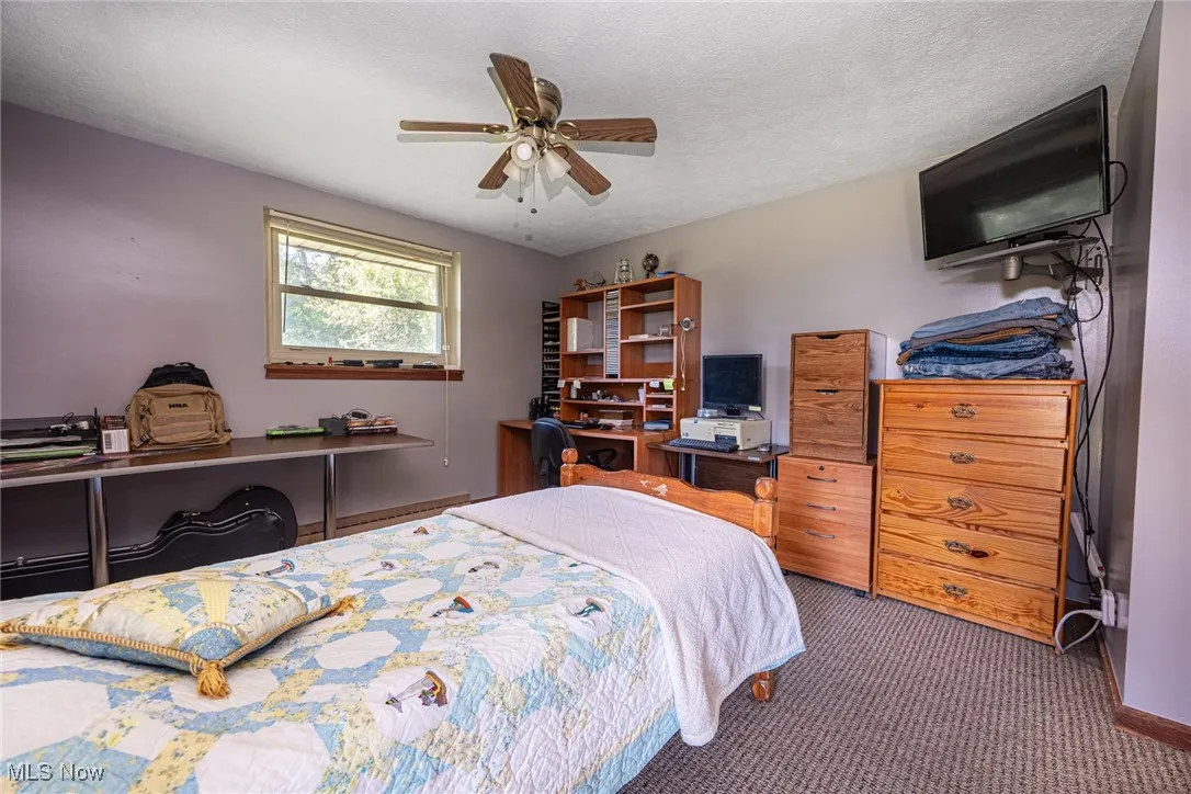Bedroom featuring dark colored carpet, a textured ceiling, and ceiling fan