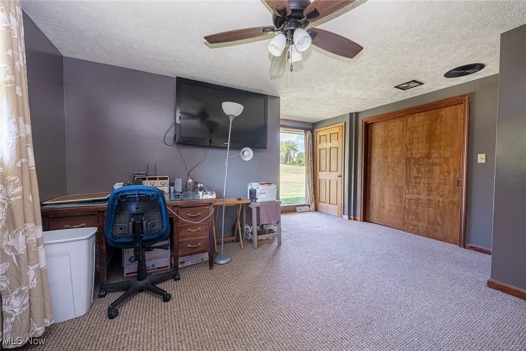 Office area featuring a textured ceiling, carpet flooring, and a ceiling fan