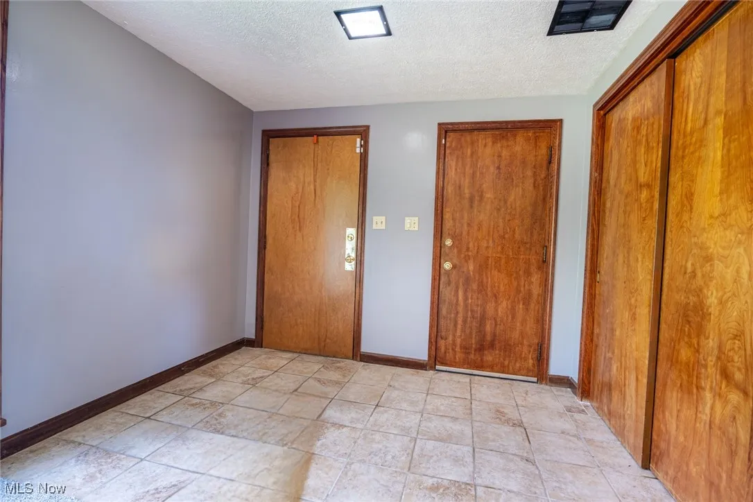 Unfurnished bedroom with a textured ceiling and multiple closets