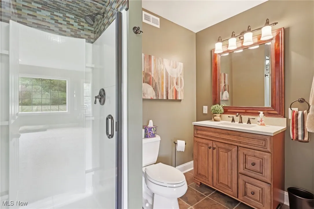 Bathroom with a shower stall, vanity, and dark tile patterned flooring