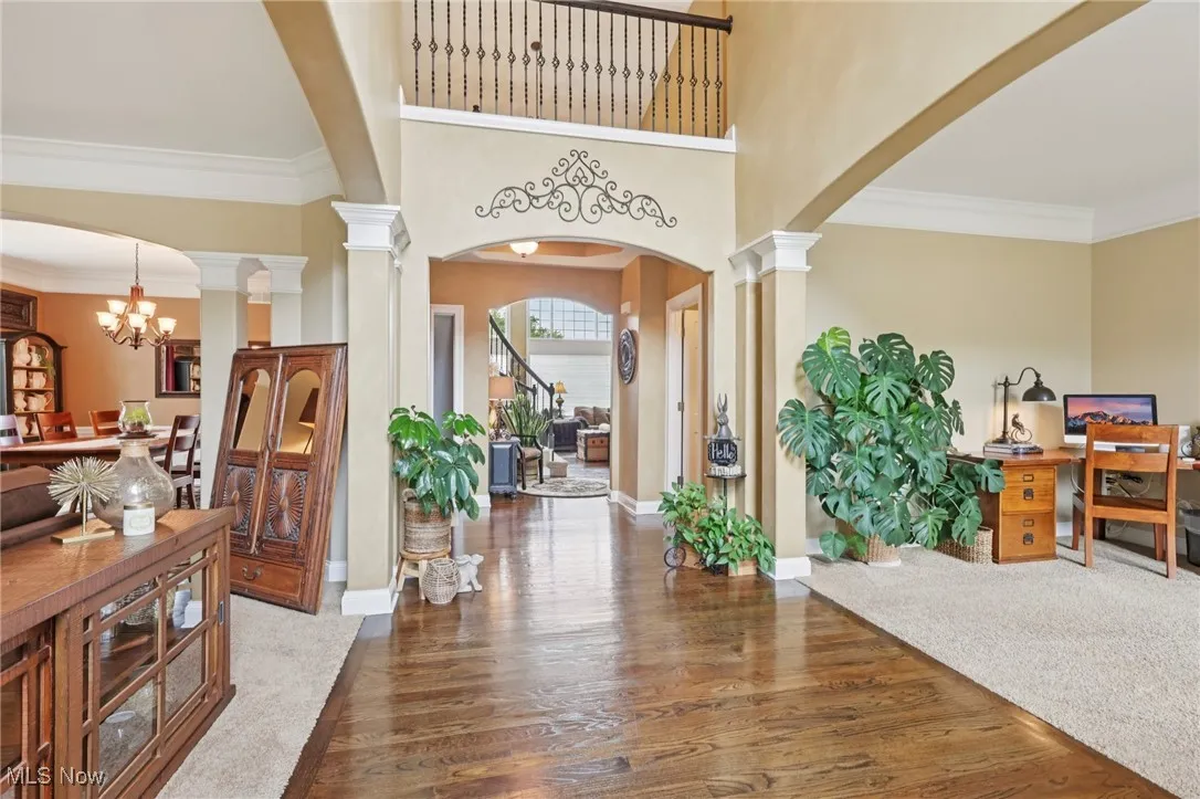 Foyer entrance featuring a towering ceiling, arched walkways, crown molding, dark wood finished floors, and a chandelier
