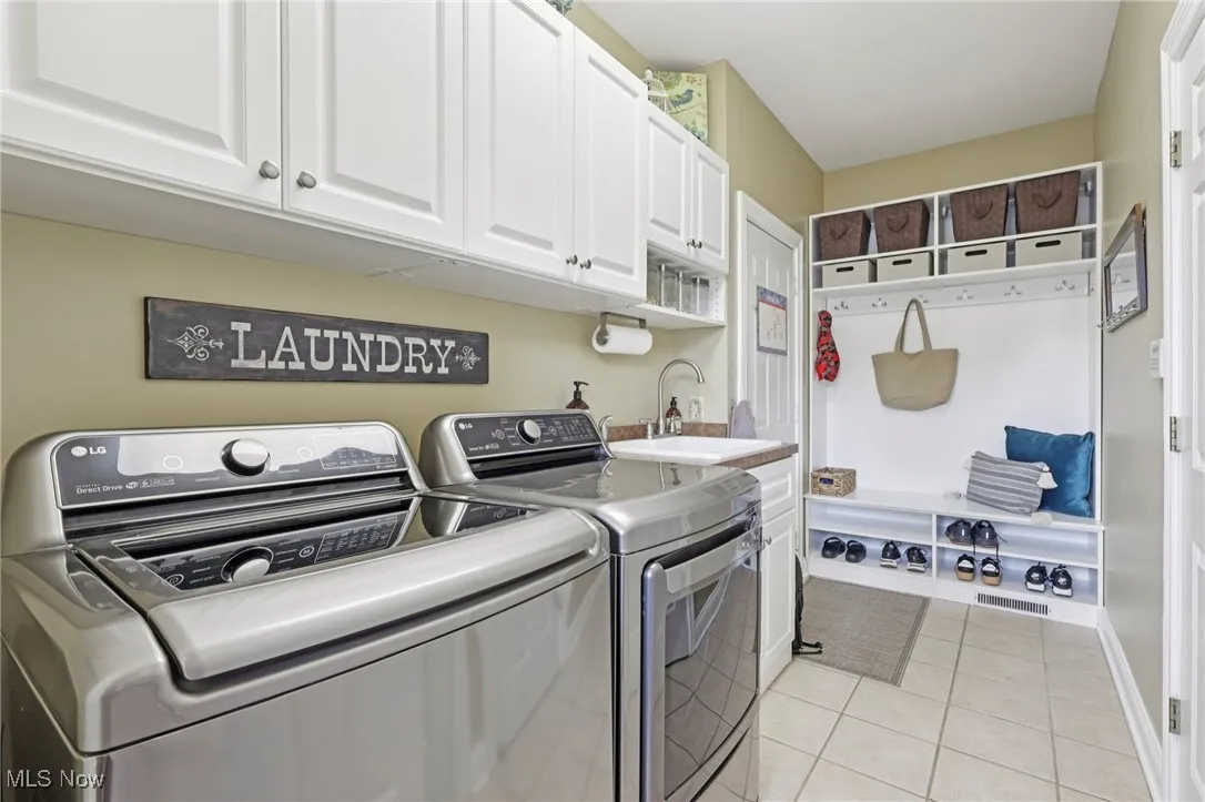 Laundry area with light tile patterned floors, cabinet space, and washer and dryer