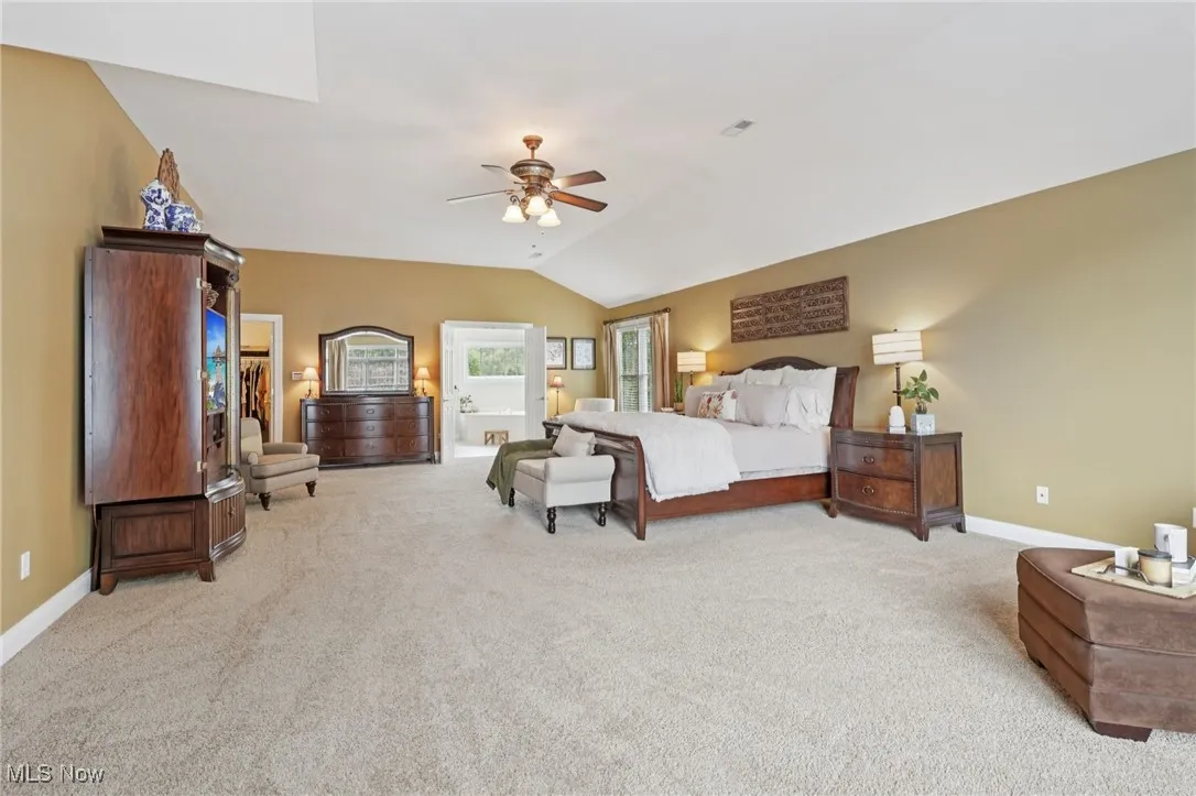 Bedroom featuring light carpet, ceiling fan, and vaulted ceiling