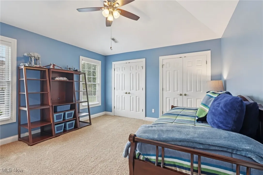 Bedroom featuring multiple closets, carpet, a ceiling fan, and vaulted ceiling