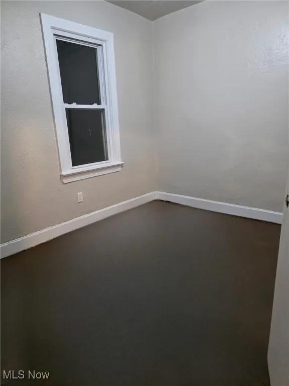 Empty room with a textured wall and finished concrete flooring