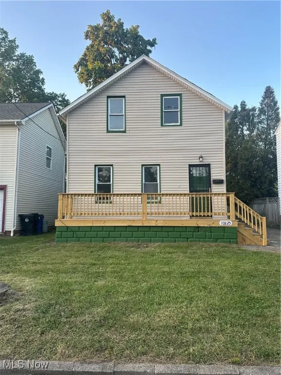 Front view of house featuring a deck and a yard