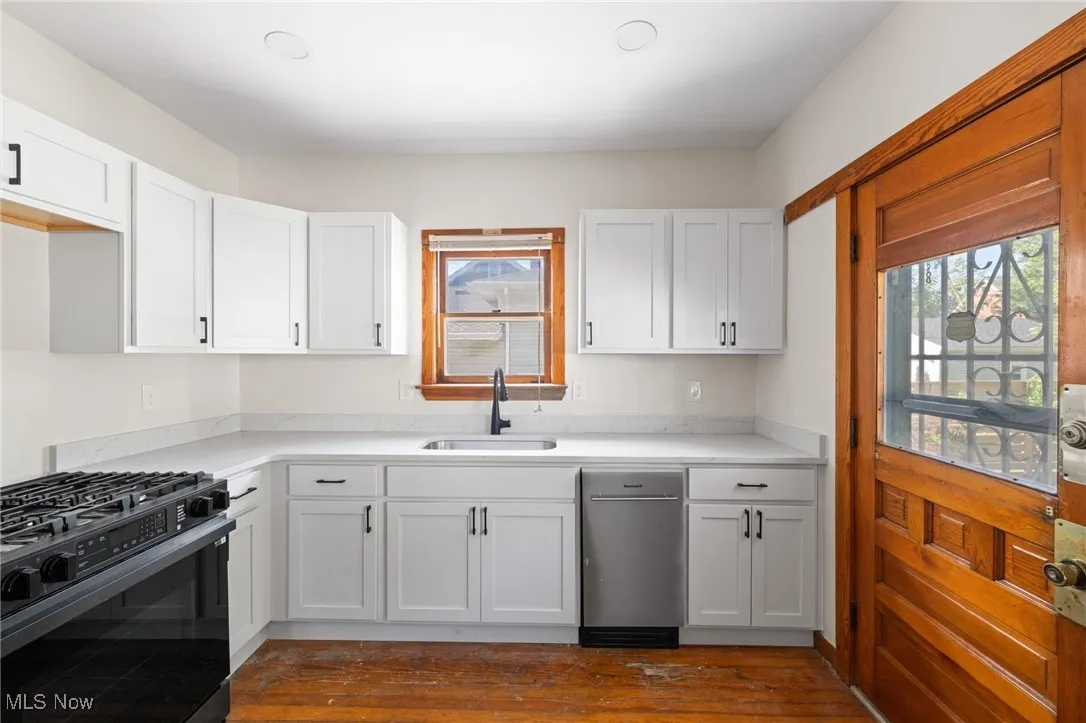 Kitchen with gas range oven, white cabinets, and dark wood-type flooring