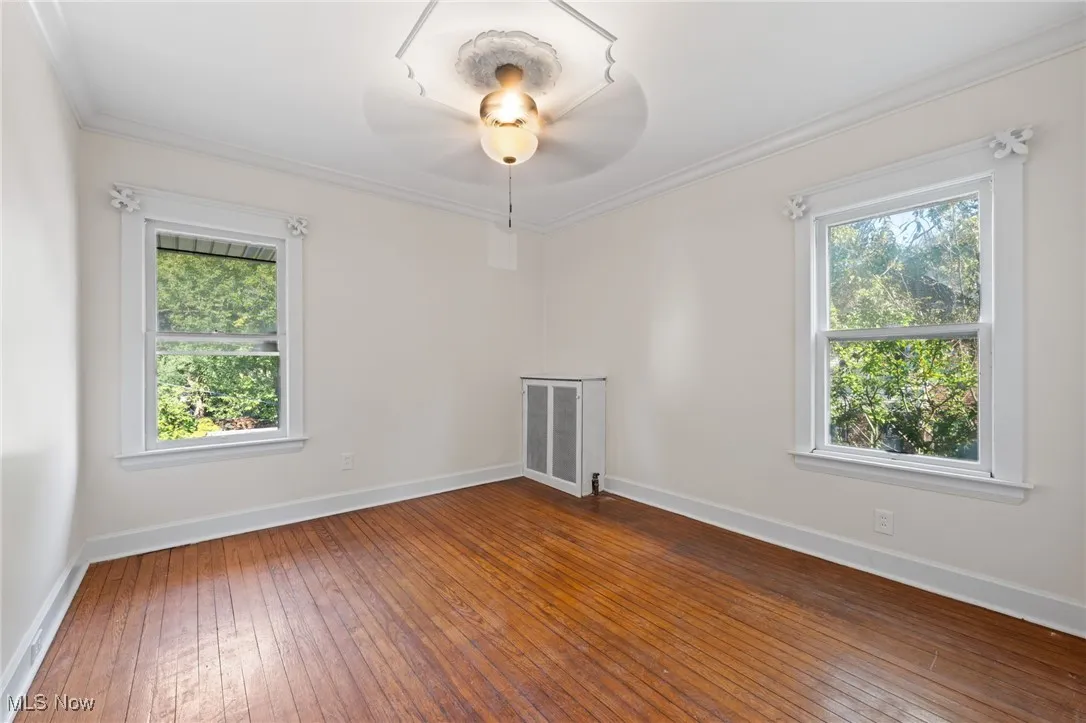 Bedroom with hardwood flooring, plenty of natural light, ornamental molding, and ceiling fan