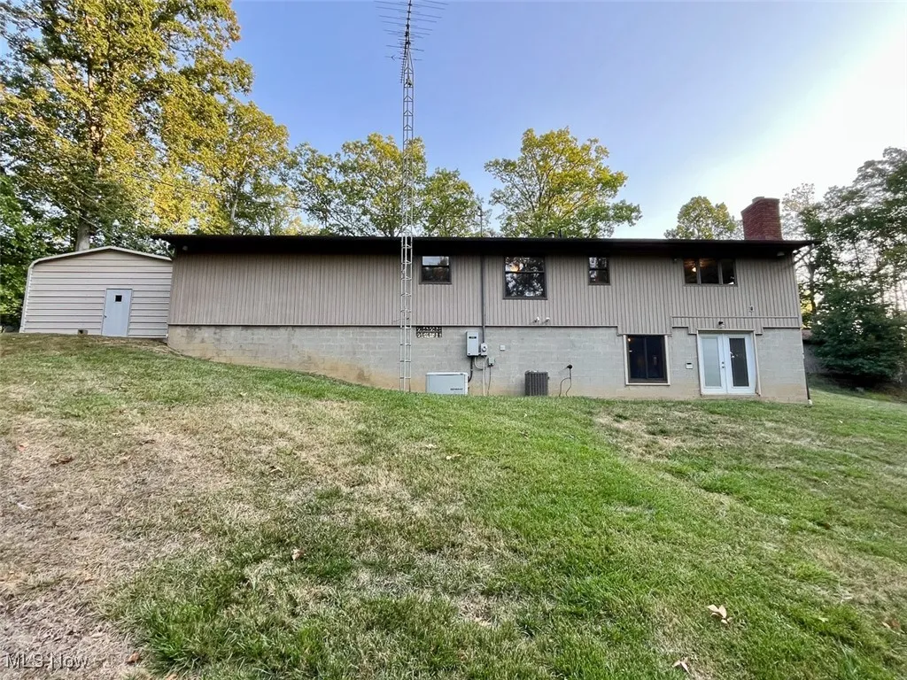 Back of property featuring a yard, a chimney, an outdoor structure, and french doors