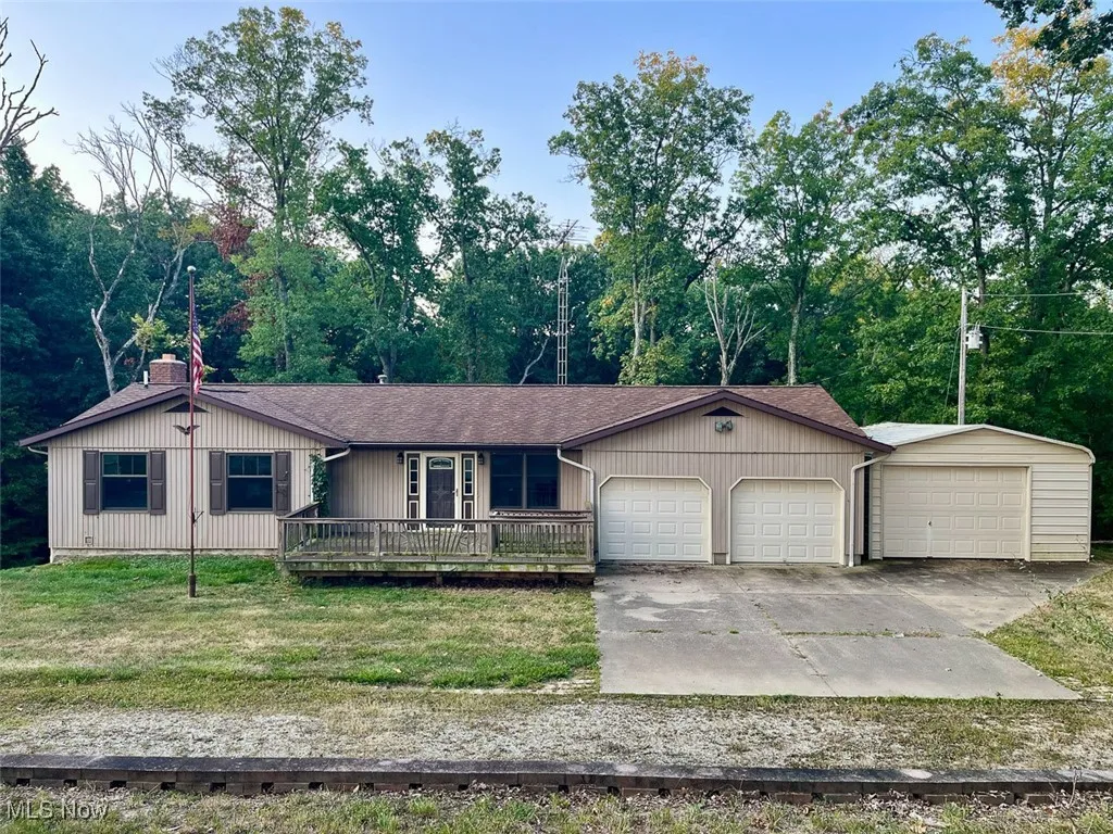 Ranch-style home featuring roof with shingles, a chimney, a garage, and a front yard
