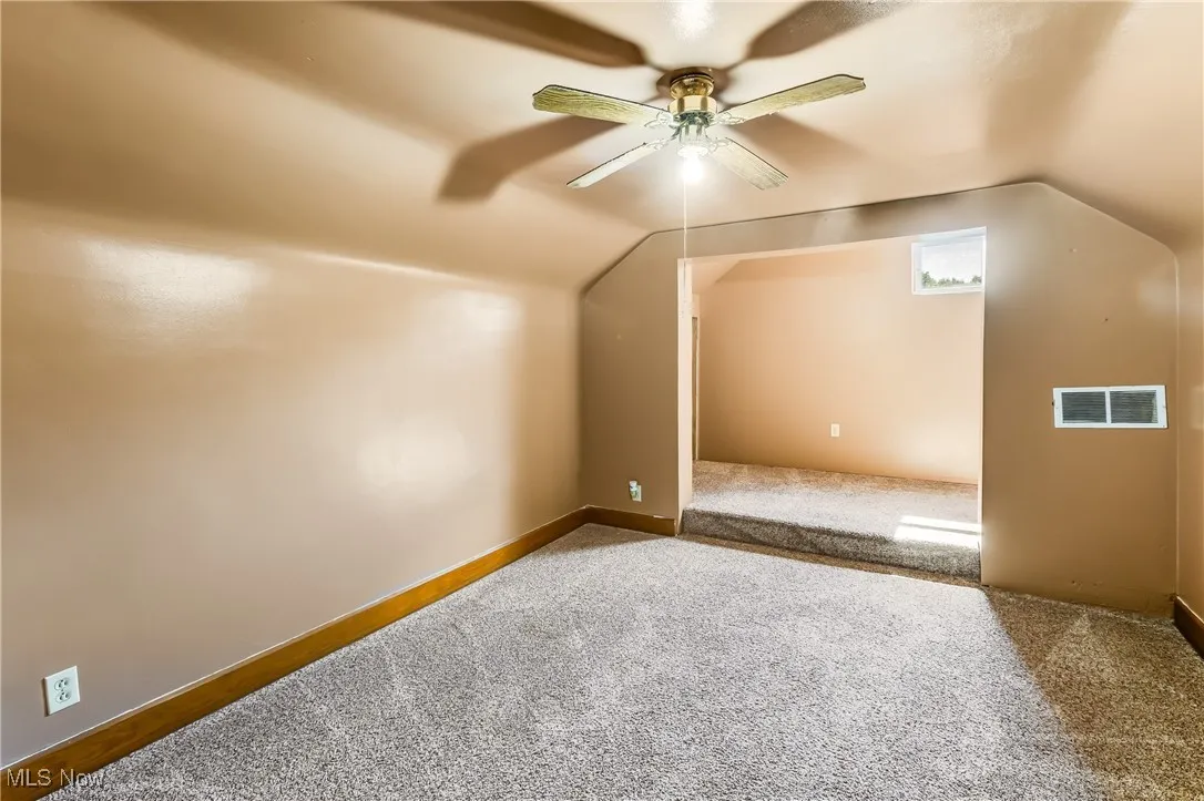 Bonus room with vaulted ceiling, carpet, and a ceiling fan