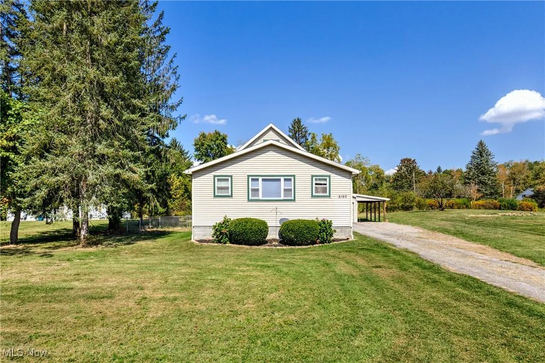 View of home's exterior with dirt driveway, a yard, and a carport