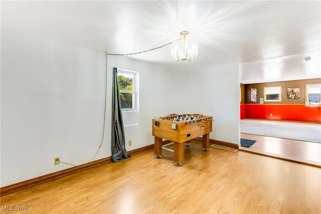 Game room featuring light wood-type flooring and a chandelier