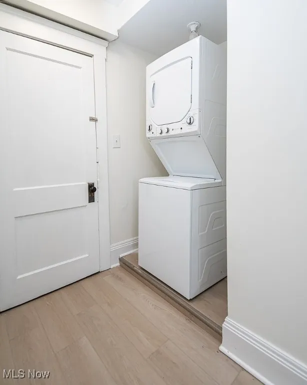 Laundry area with light wood finished floors and estacked washer and dryer