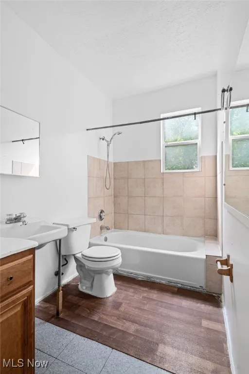 Bathroom with shower / bath combination, vanity, dark wood-style floors, and a textured ceiling