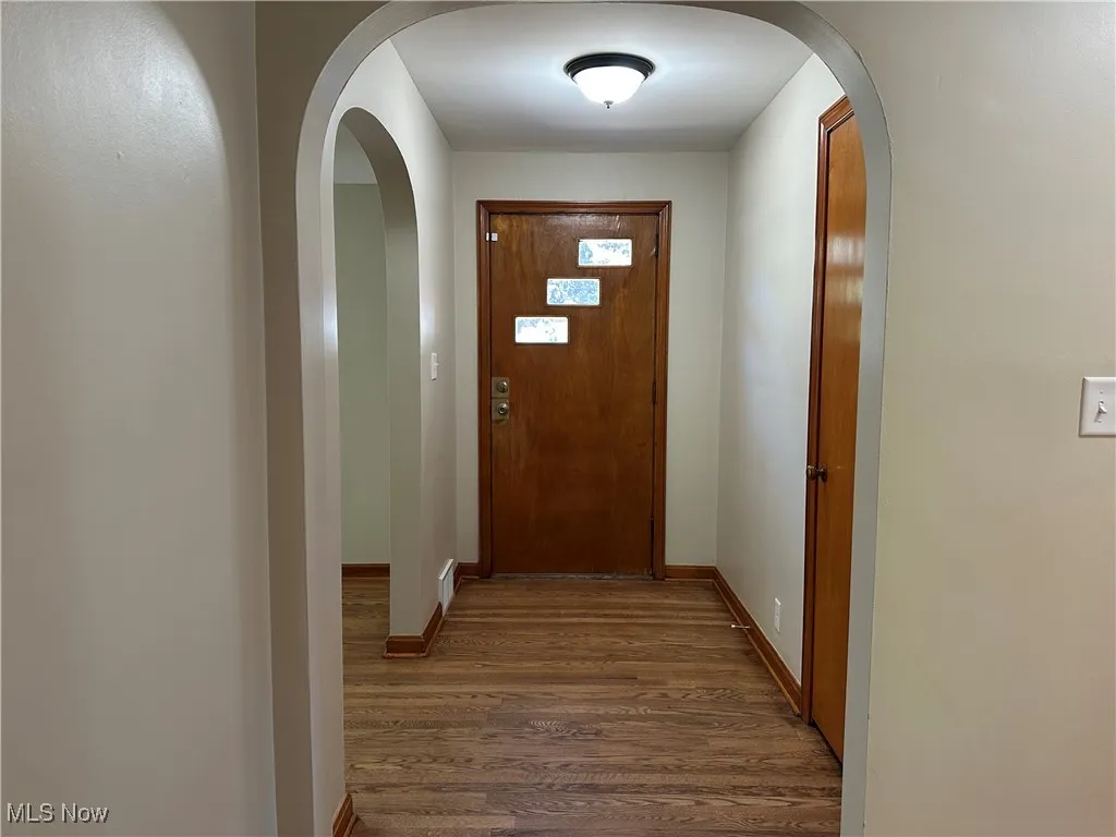 Entryway with arched walkways and wood finished floors