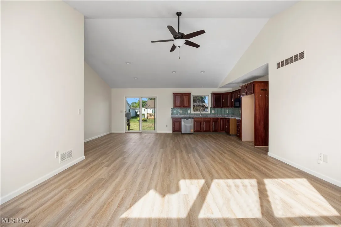 Unfurnished living room with light wood-style floors, high vaulted ceiling, and ceiling fan