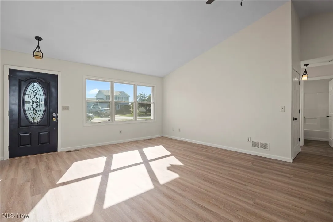 Entrance foyer with light wood-style flooring, high vaulted ceiling, and ceiling fan