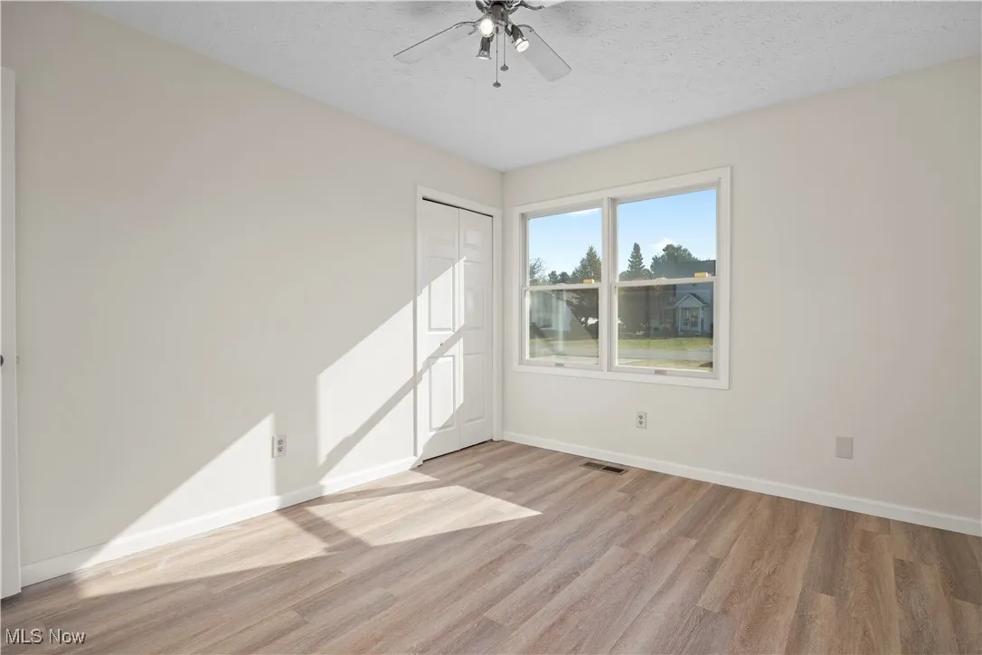 Spare room featuring light wood-type flooring, a textured ceiling, and a ceiling fan