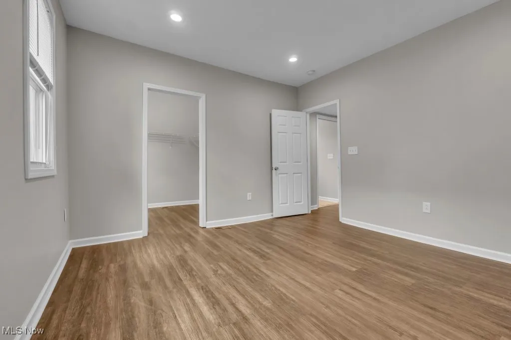 Unfurnished bedroom featuring a spacious closet, wood finished floors, and recessed lighting