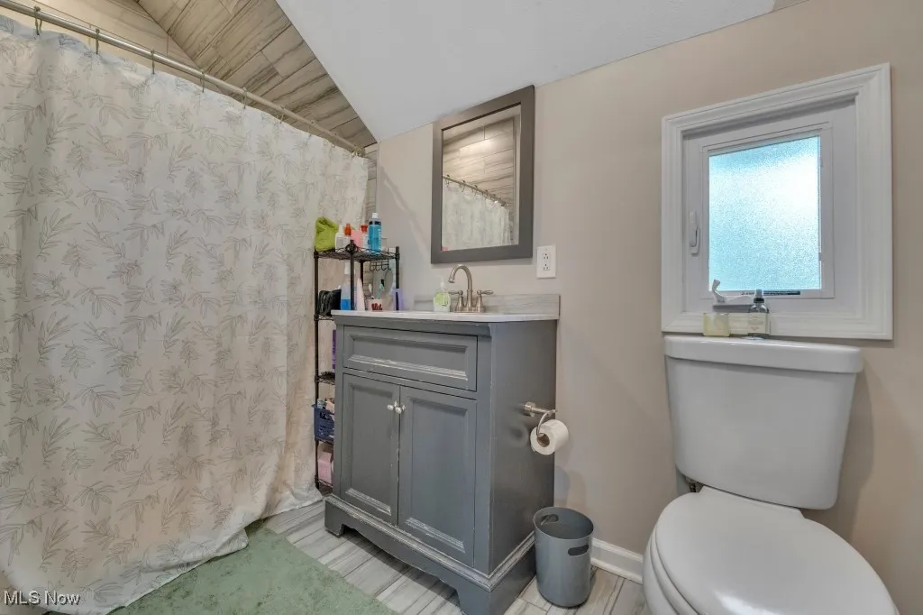 Full bath featuring vanity, a shower with shower curtain, and lofted ceiling