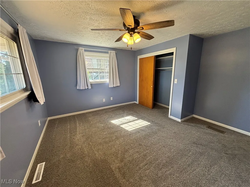 Unfurnished bedroom featuring carpet flooring, a closet, ceiling fan, and a textured ceiling
