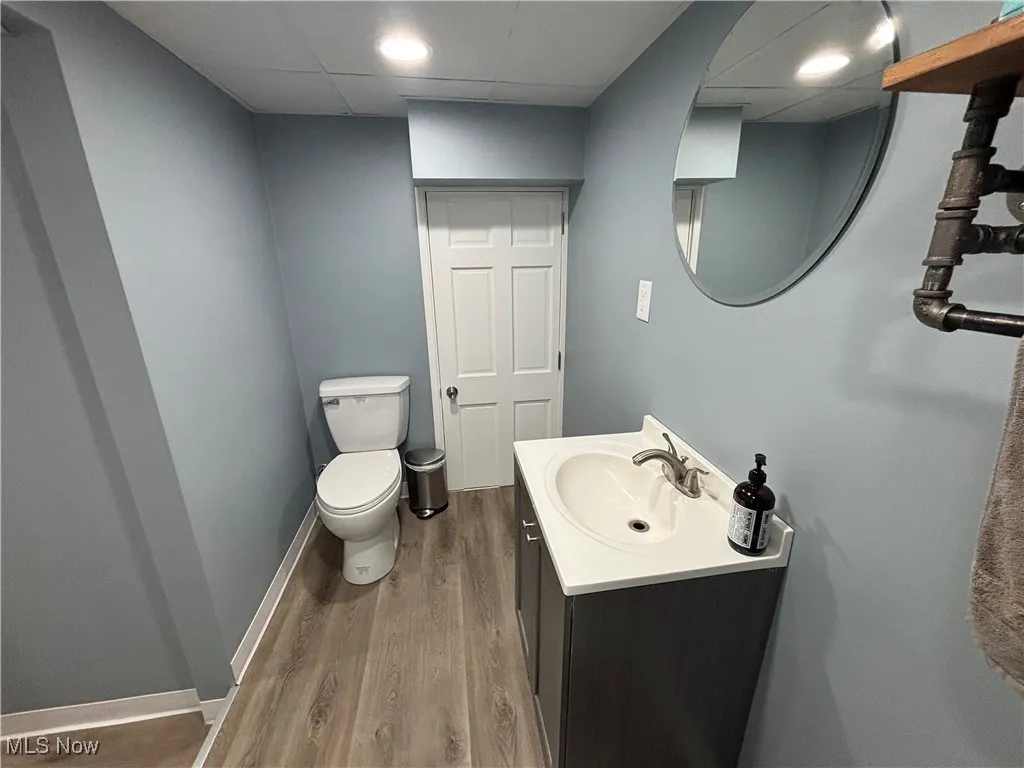 Half bathroom featuring a drop ceiling, vanity, and light wood-type flooring