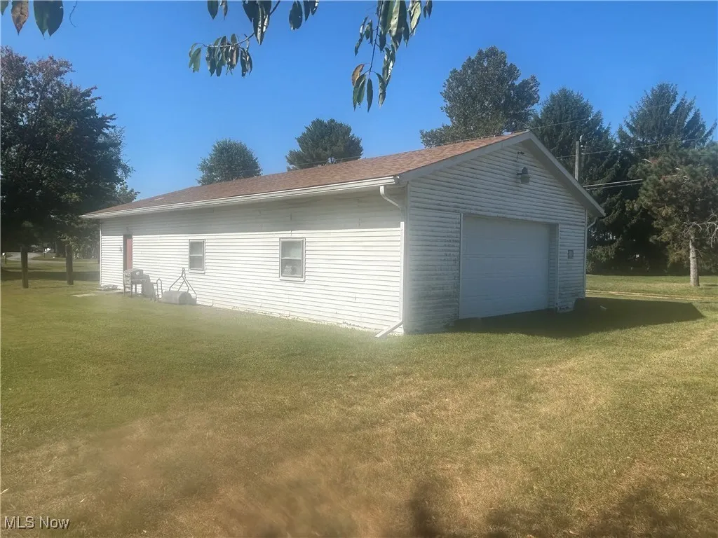 View of side of property with a lawn and a detached garage