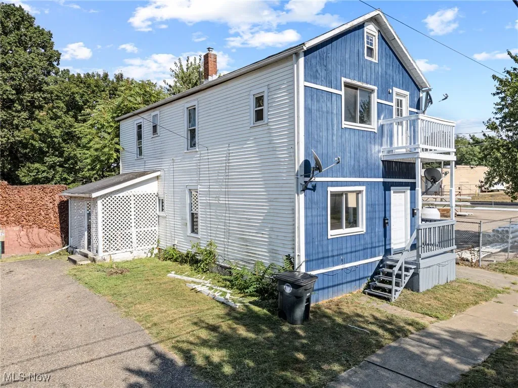 View of side of property with a chimney and a balcony