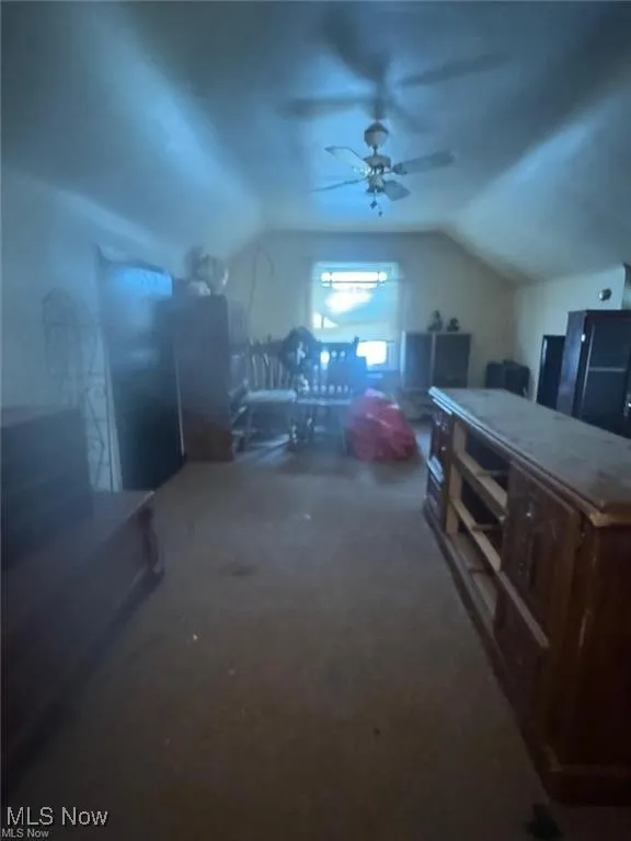 Additional living space with lofted ceiling, dark colored carpet, and a ceiling fan