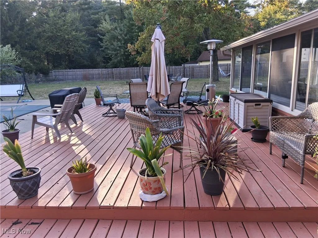 Wooden deck featuring a fenced backyard, a sunroom, and outdoor dining area