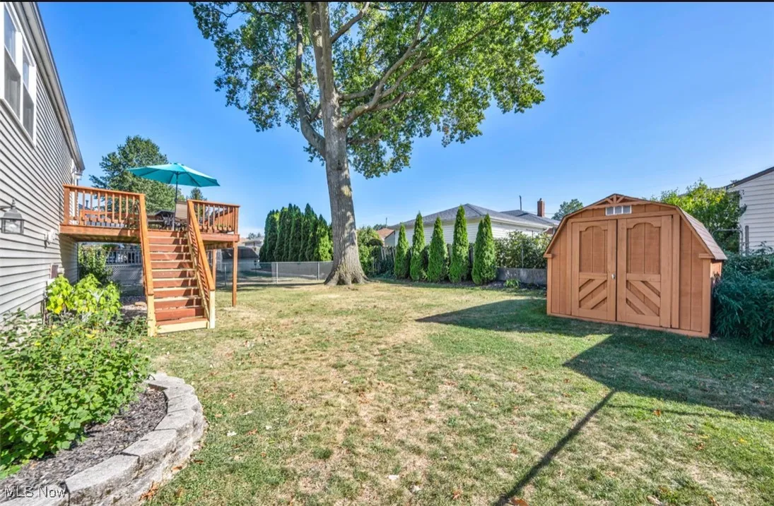 View of yard featuring stairway, a wooden deck, and a storage unit