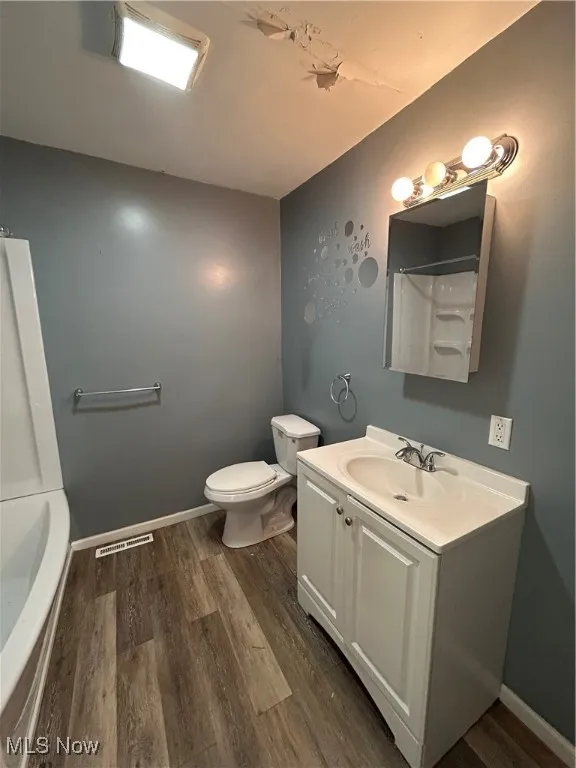Full bath featuring dark wood finished floors, vanity, and washtub / shower combination