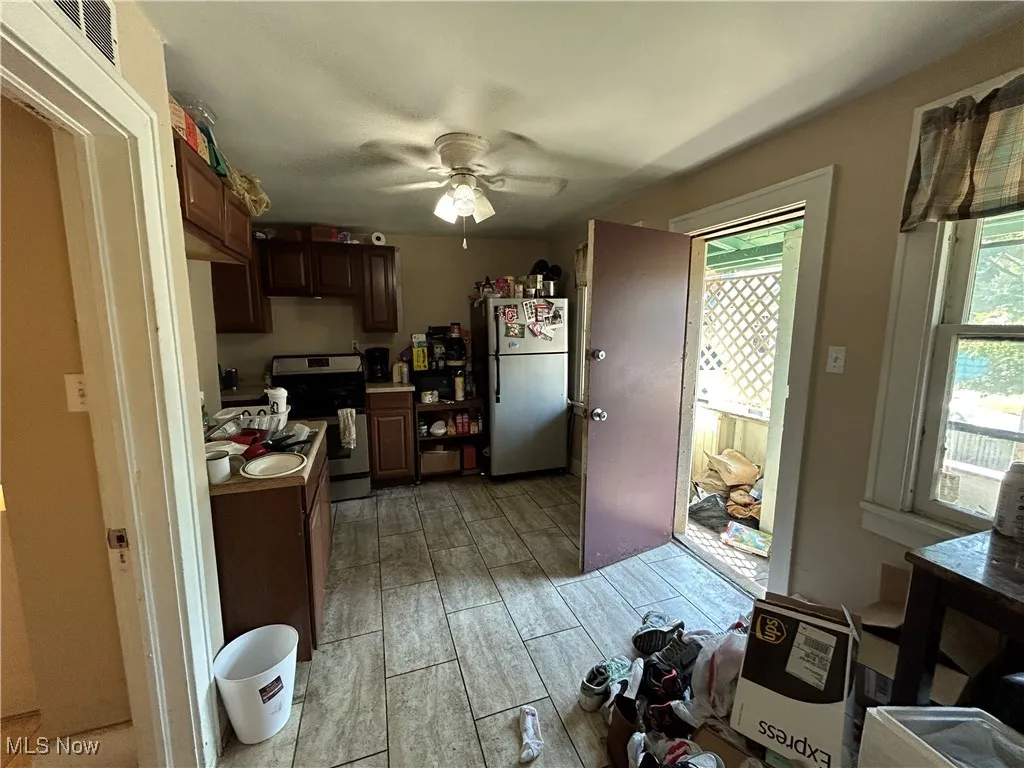 Kitchen with freestanding refrigerator, stainless steel electric range oven, ceiling fan, wood tiled floors, and dark brown cabinetry