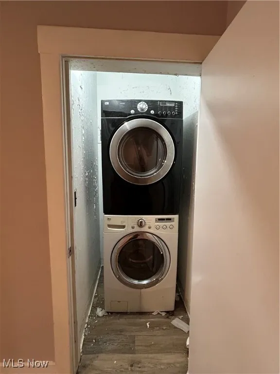 Laundry area with stacked washing machine and dryer and wood finished floors
