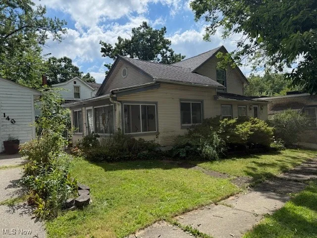 View of side of home with a sunroom and a yard