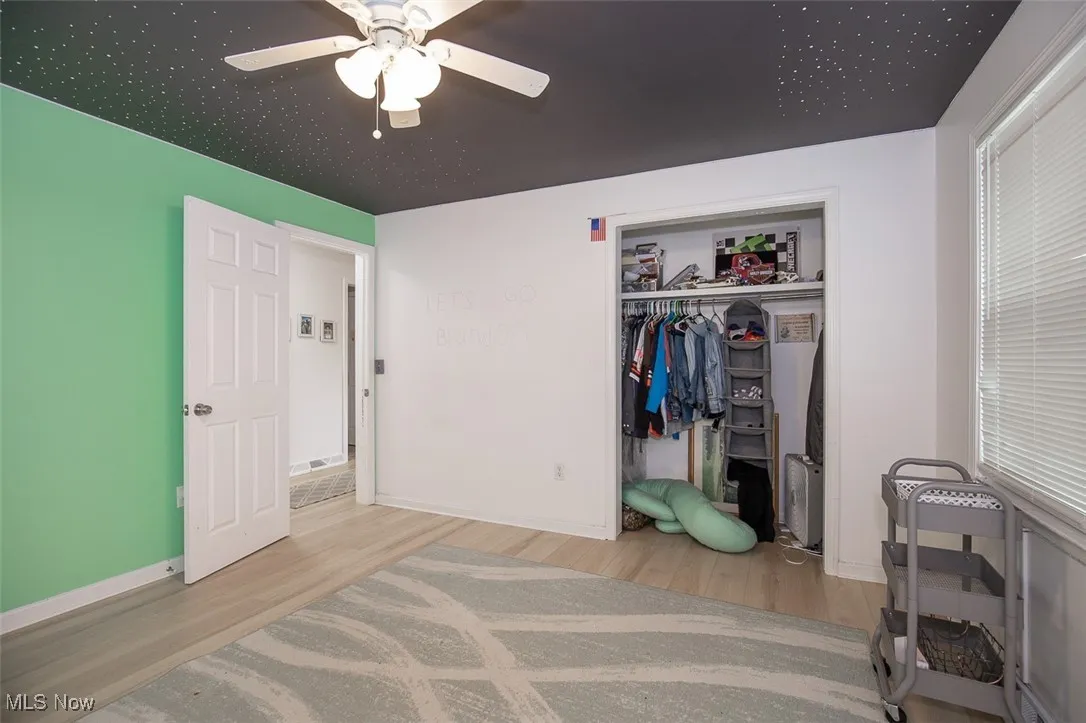 Bedroom featuring light wood finished floors, ceiling fan, and a closet