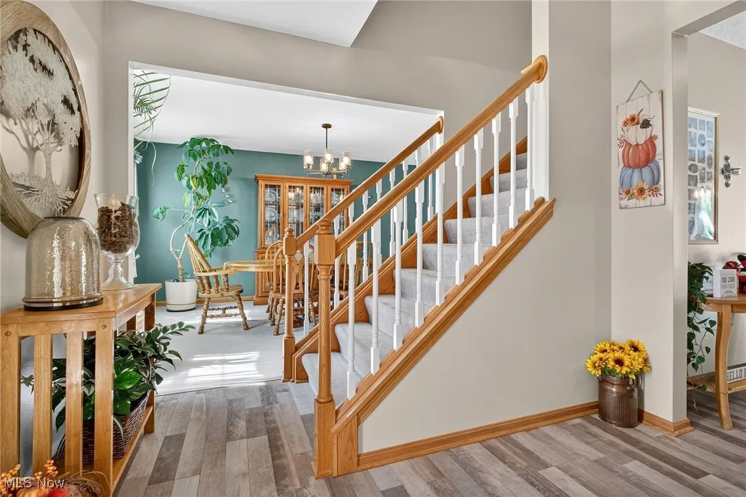 Stairway featuring wood finished floors and a chandelier