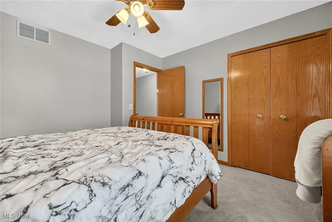 Bedroom with light colored carpet, a closet, and ceiling fan